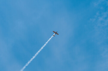 An airplane in the blue sky with beautiful clouds makes aerobatics.