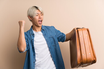 Young asian man over isolated background holding a vintage briefcase
