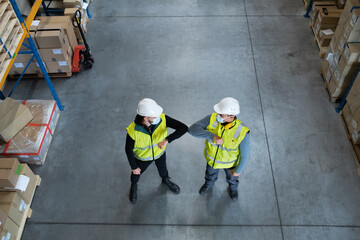Top view workers with face mask greeting indoors in warehouse, coronavirus concept.