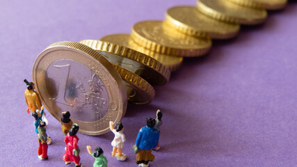 Group of miniature people standing in front of falling row of euro coins on violet background