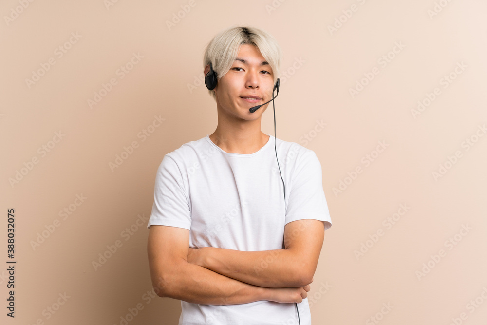 Wall mural Young asian man over isolated background working with headset