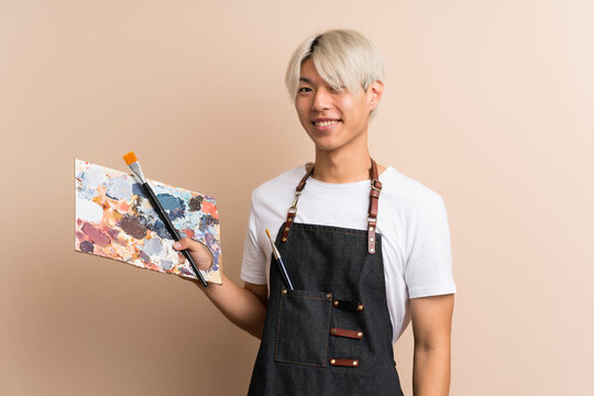 Young asian man over isolated background holding a palette