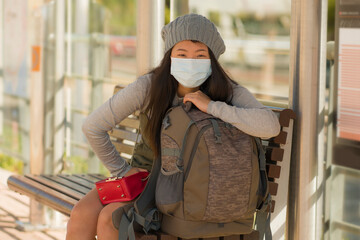 young beautiful and happy tourist Asian woman traveling during new normal - attractive Japanese girl with backpack waiting for train at station platform doing tourism while virus