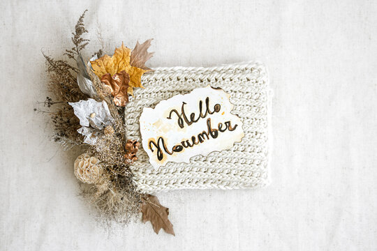 Autumn composition Hello Nowember with knitted element in the center on white background top view.