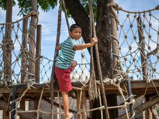Boy climbing a rope ladder In the playground