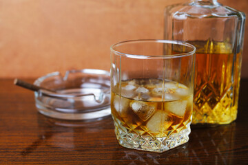 Whiskey with ice on a wooden table close-up, place for your text.