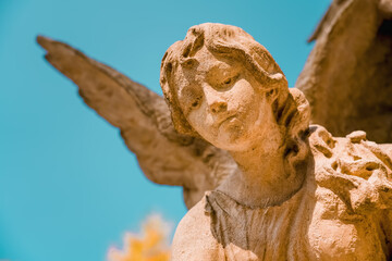 Beautiful angel in the sunlight against blue sky. Antique stone statue.