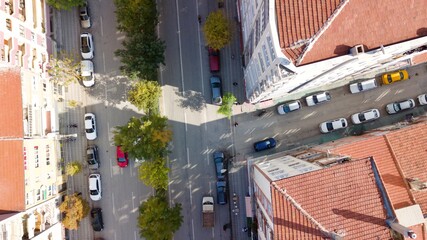 Aerial view of the city traffics at the center. Vehicles are moving on the road between buildings.