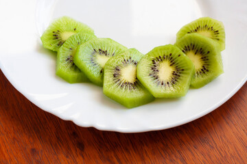Slices of ripe kiwi on a white plate on the table