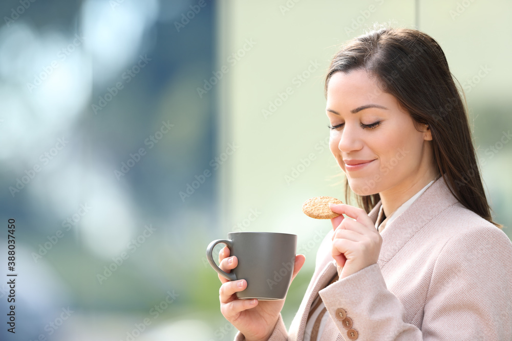 Wall mural Entrepreneur eating cookie and drinking coffee at breakfast