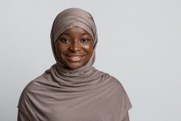 Portrait of beautiful african muslim woman in hijab over light studio background