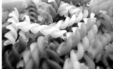 Obraz premium black and white pasta fusilli on wooden oak bord close-up