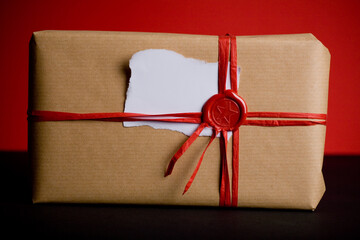Vintage Christmas gift with red wax seal and ribbons with a blank white piece of paper on top. 