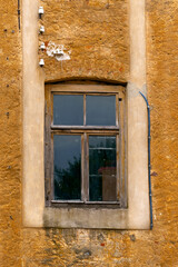 An old window in a wooden frame in the opening of an old house.