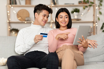 Korean Couple Shopping Online Via Tablet And Credit Card Indoor