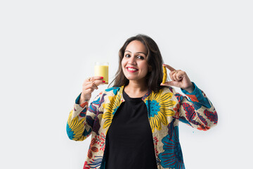 Asian Indian pretty Girl drinking turmeric milk in a glass