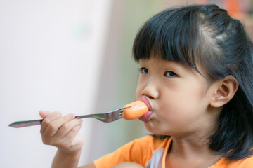 A 3-year-old Asian girl eating hot dog.