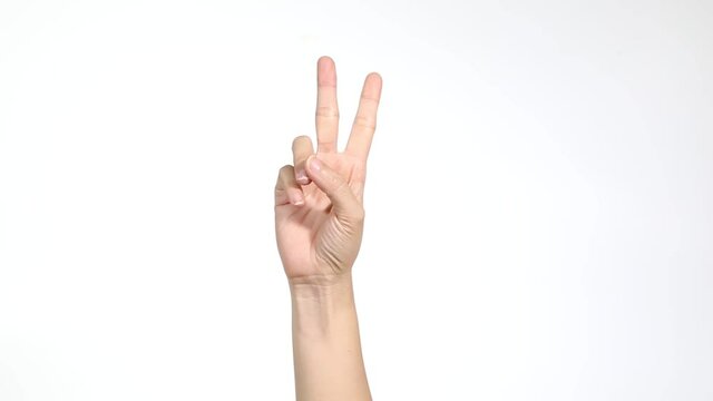 Woman raising two fingers up and showing peace or victory symbol or letter V. Female one hand holding two fingers up in sign language on light background. Fingernails with fresh red glossy manicure.