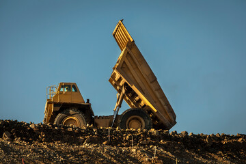 A very large yellow haul dump truck on a ridge at a construction site involved in grading...