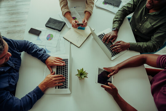 High angle shot of workers gathered together brainstorming ideas for new project sitting around table in board room