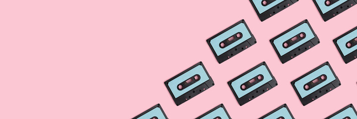 Cassette tapes pattern on a pink pastel background. Creative banner with place for text.