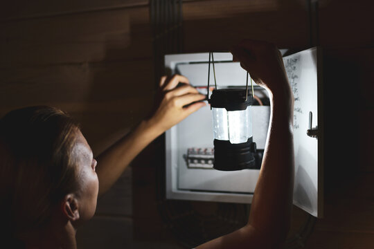 Emergency Power Outage In The House. Woman With A Flashlight Looks