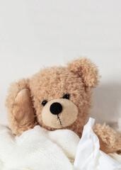 Cold, flu or allergy. Cute teddy in bed sneezing