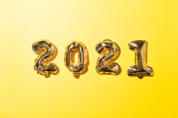 Naklejka premium 2021 gold balloons on yellow paper background. Christmas or New Year festive concept. Top view and flat lay.