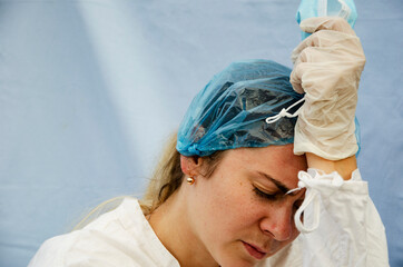 A tired doctor after a hard day with coronavirus patients. An exhausted doctor from a large number of people infected with coronavirus. Doctor in a medical mask and gloves in a protective suit works 