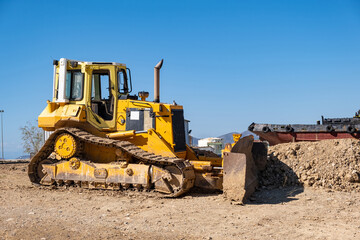 Yellow bulldozer at Drapetsona shipyard, Piraeus, Greece. Blue sky background.