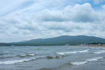 sea waves with foam. beach and mountains in the distance