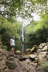 mujer de senderismo mirando paisaje de cascada y lago 