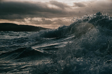 moody waves crash with sun breaking through