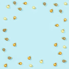 New Year glass balls golden colored, small shiny toys on blue paper. Holiday Christmas frame.