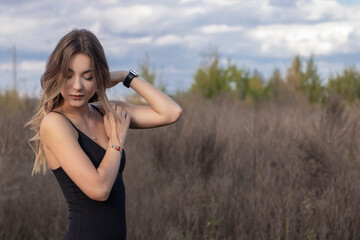 sensitive attractive slim brunette in skinny fitting black dress in the field. autumn, yellow...