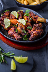 Roasted chicken wings in barbecue sauce with lime and baked potatoes