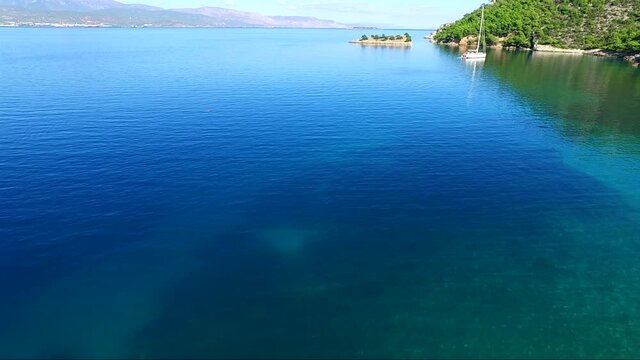 Aerial view of Siderona bay, Corinthia, Greece, on a lovely bright day in a calm blue and turquoise sea, with sailing boat