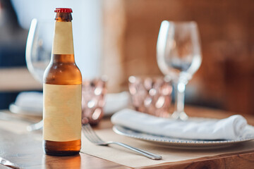 Beer bottle with yellow label, on table with plate and glass in restaurant