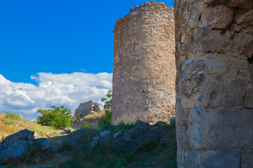 Fototapeta na wymiar Ruins of an ancient fortress with the remains of a wall and dilapidated watchtowers