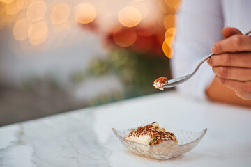 white ice cream in a plate with chocolate girl holding a piece on a spoon bokeh background
