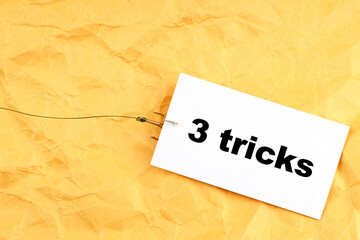 paper on a fish hook with 3 tricks written on it