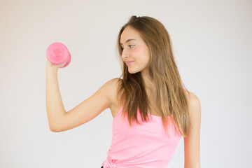 Attractive young fitness woman holding dumbbell. Studio shot.