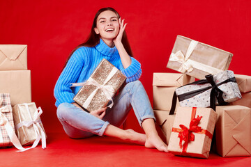 girl in a knitted hat with New Year's gifts on a red background.