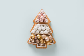 Christmas greeting card pastel shiny baubles in shape of tree on blue. Top view.