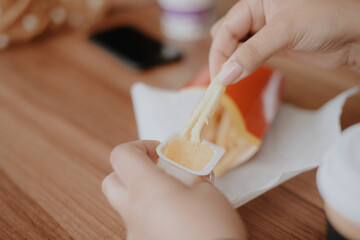 Close-up of a woman's hands with French fries in a street cafe