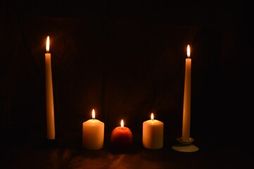Group of burning candles on black background.
