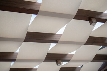 summer ceiling of wooden beams and white fabric and white sky
