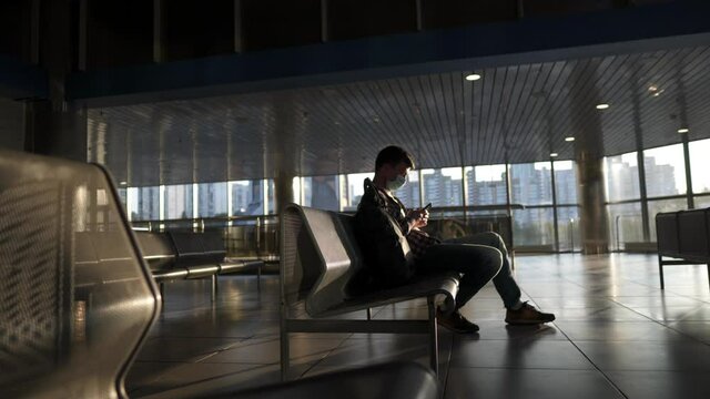 Waiting for flight at an empty airport. Man sitting on chair in empty airport lounge. Flights canceled. Problems with flights during quarantine. The collapse of airlines. Covid 19, coronaviruse