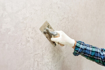 A worker makes a decorative plaster with a spatula