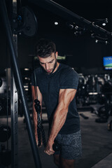 Fototapeta na wymiar Good looking handsome male athlete exercising in modern fitness gym. Dark muddy light with strong shadows. Indoors sport concept.